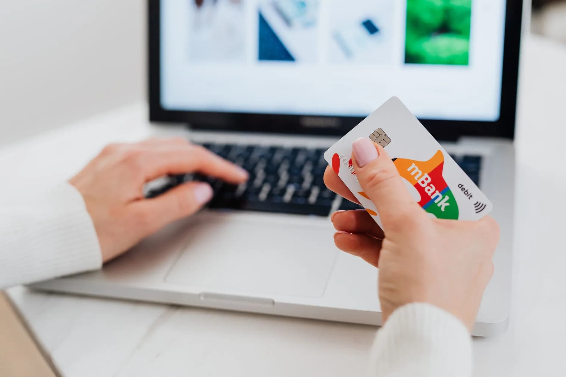 Primo piano di mani che utilizzano un laptop e tengono una carta di credito per una transazione online.