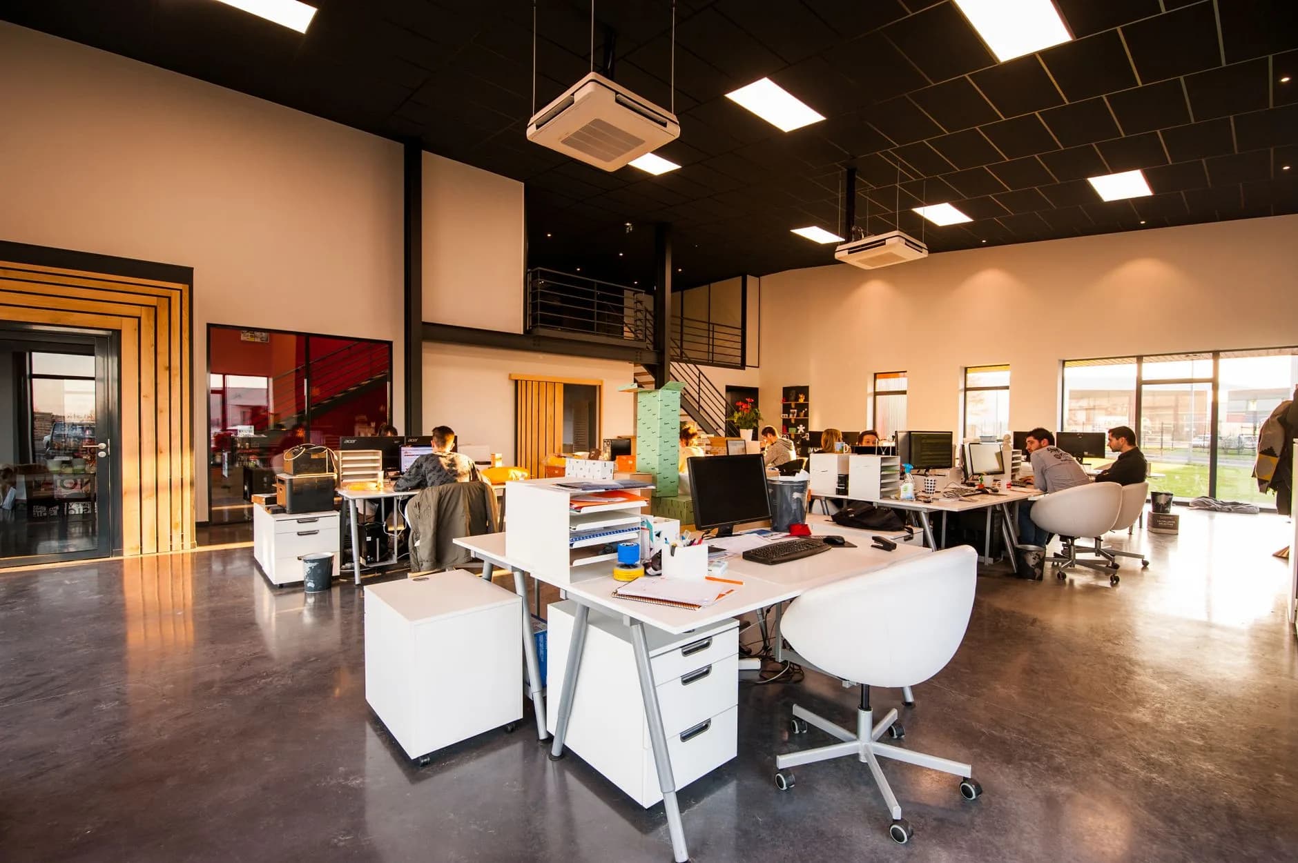 Un ufficio spazioso e moderno in open space con luce naturale e dipendenti che lavorano alle scrivanie.