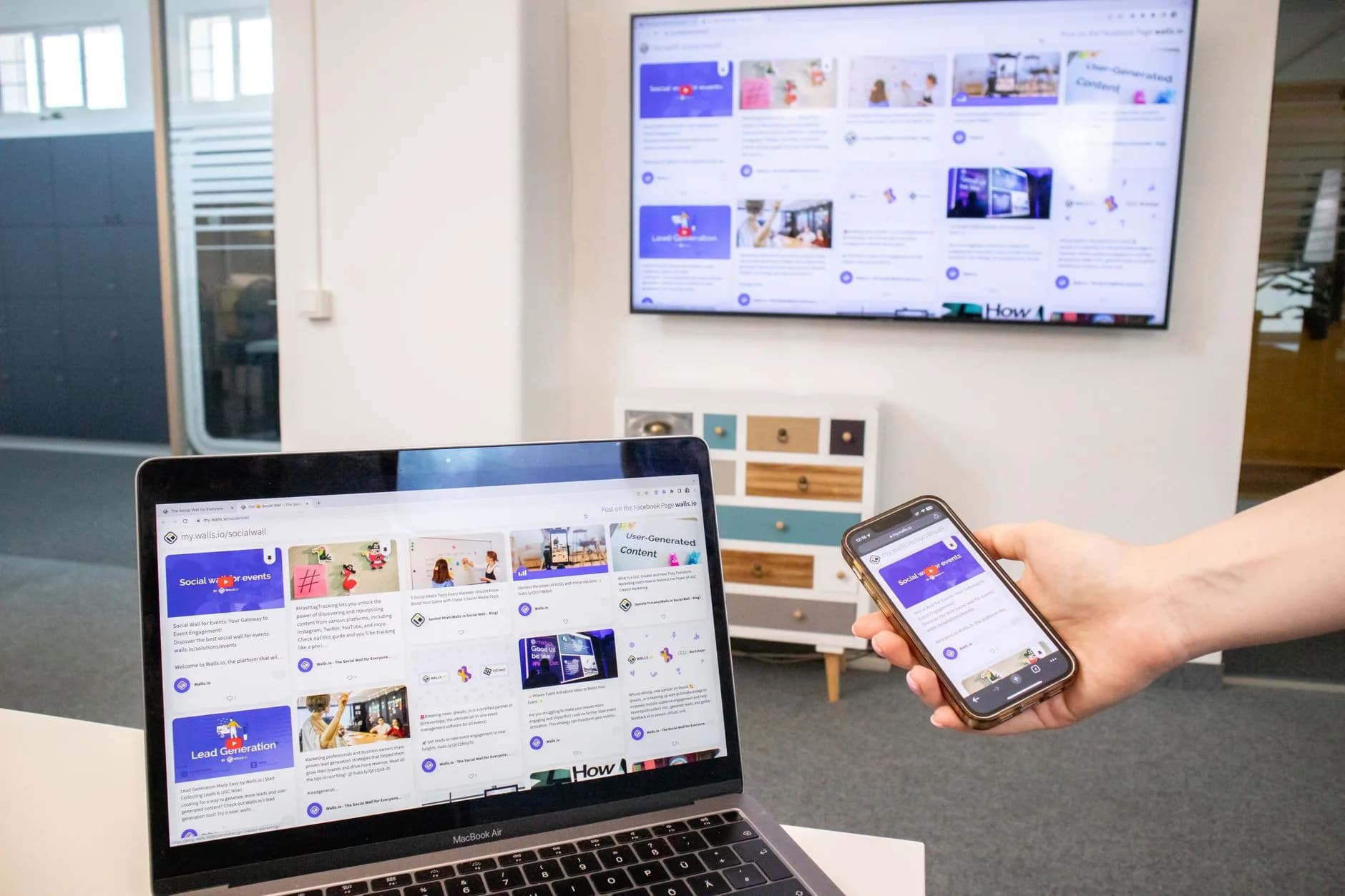Dispositivi digitali tra cui un laptop, un telefono e una TV in un ambiente d'ufficio moderno che mostra la sincronizzazione dei contenuti.