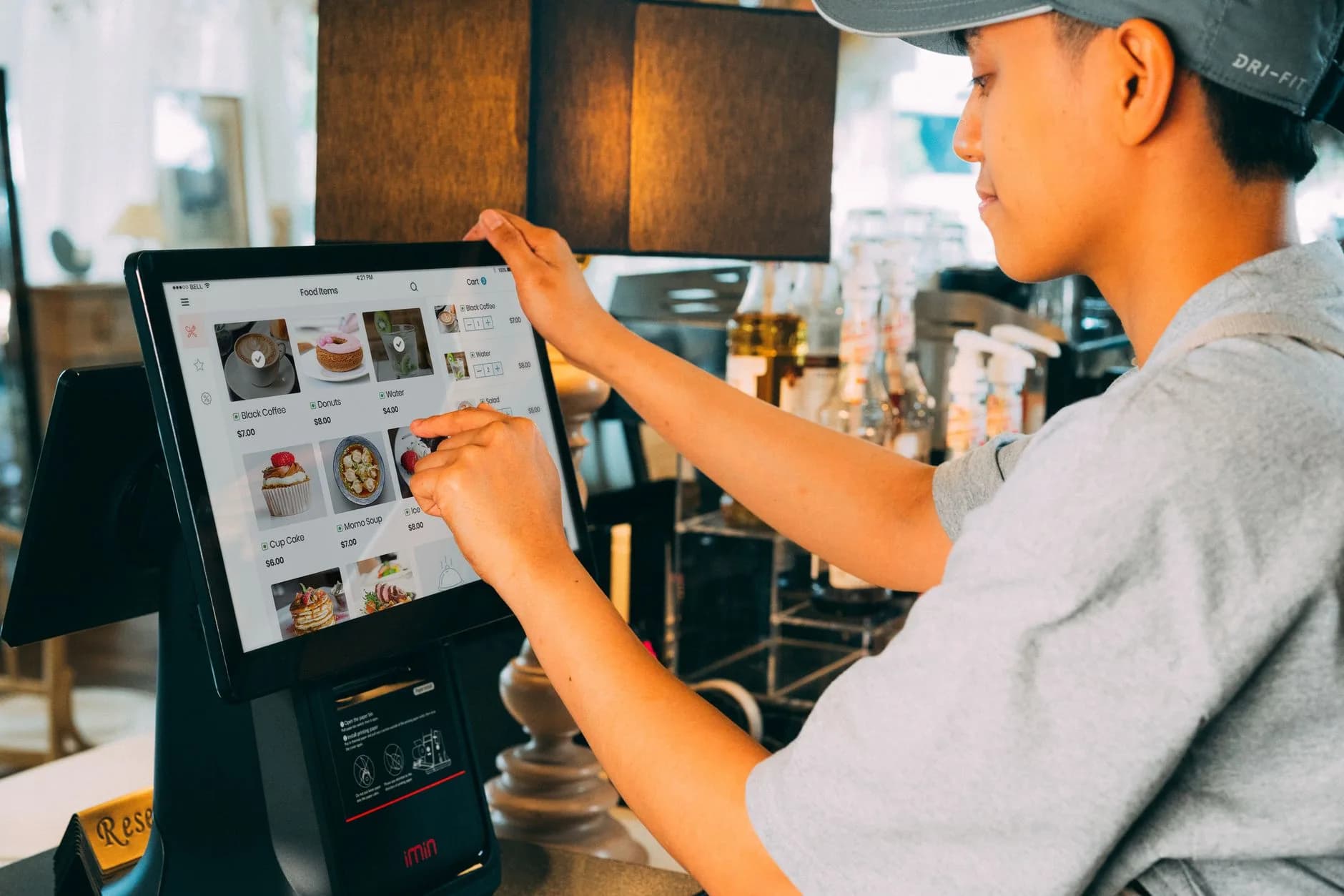 Un lavoratore di caffetteria che naviga in un sistema moderno touchscreen per gestire gli ordini in modo efficiente.